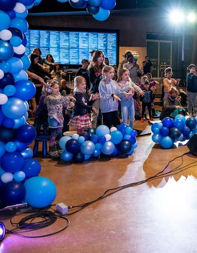 Des jeunes dansent dans une salle remplie de ballons bleus. Visibilité masquée.